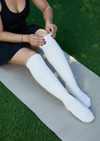 Model wearing the Studio Grip Warmer in Ivory, pulled up, seated