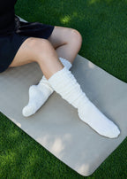 Model wearing the Studio Grip Warmer in Ivory, slouched down, seated